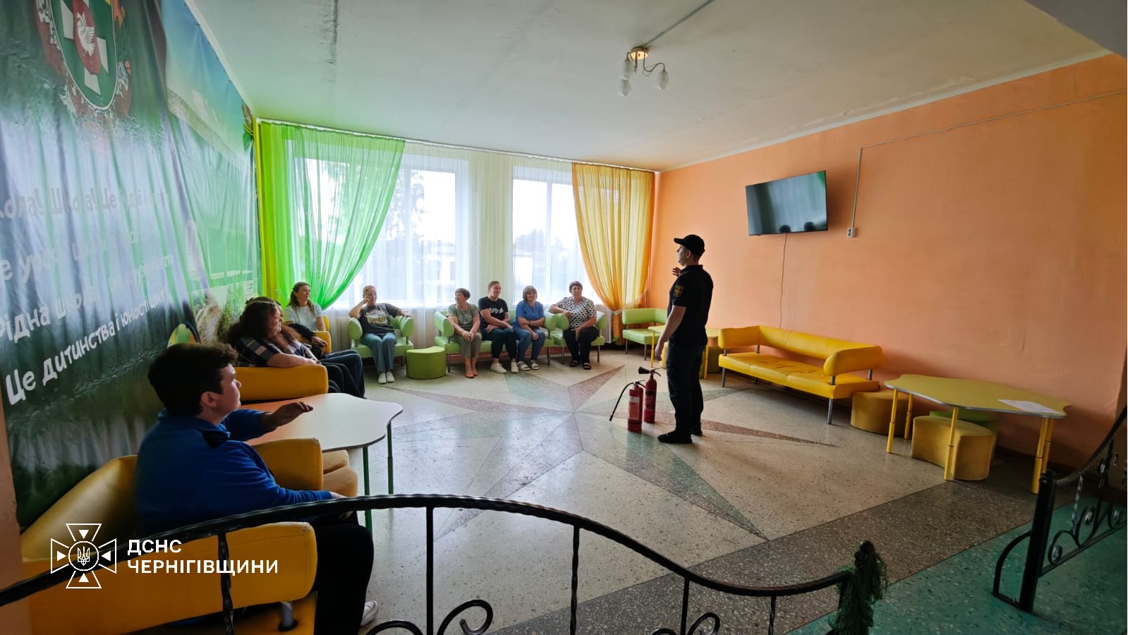 Фотографія офіцер-рятувальник виступає перед людьми у залі